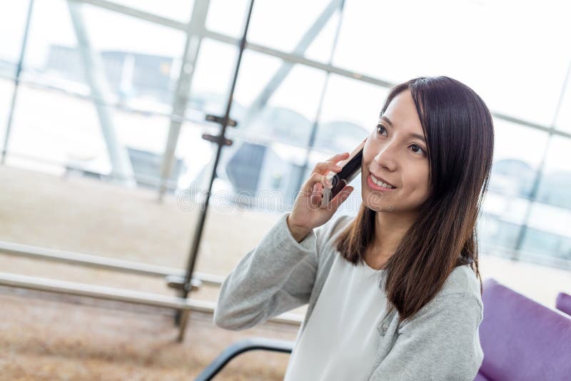Conversazione della donna al telefono cellulare in aeroporto fotografie stock libere da diritti Conversazione della donna al telefono cellulare in aeroporto fotografie stock libere da diritti