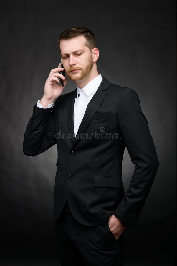 Conversazione scettica dell'uomo d'affari seria sullo smartphone fotografia stock Conversazione scettica dell'uomo d'affari seria sullo smartphone fotografia stock