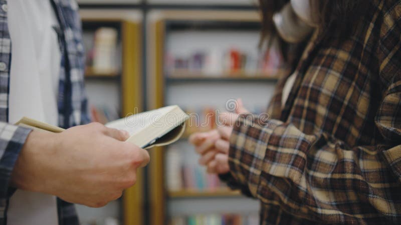Conversazione tra due persone su un libro in una comoda biblioteca nel pomeriggio video d archivio