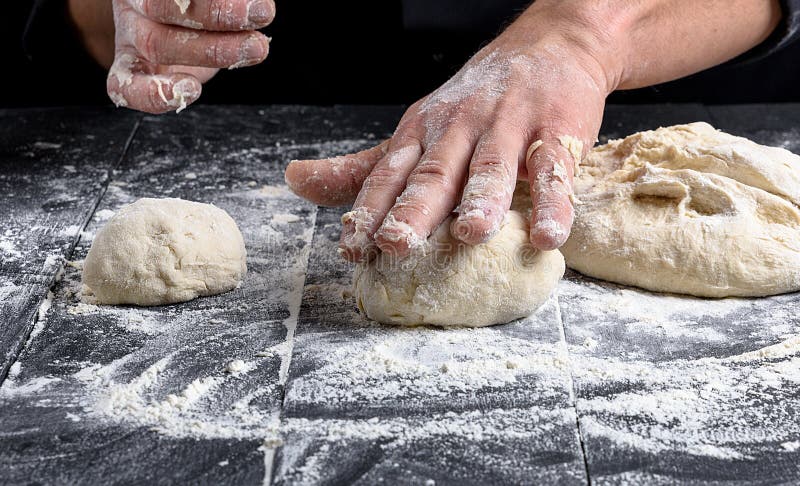 Cook making dough balls on a black wooden table