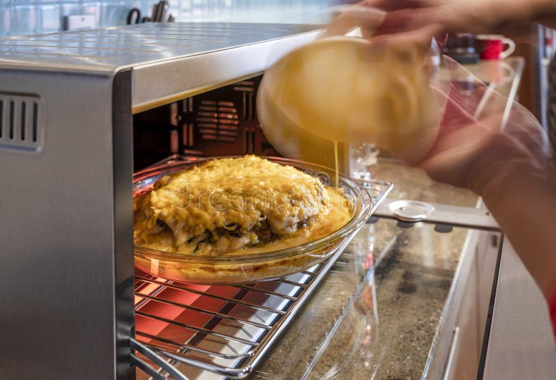 Cook nalewa kumberland w mięsnego kulebiaka z pieczarkami i warzywa i ser piec w szklanej niecce na kratownicie w elektrycznym pi obrazy stock Cook nalewa kumberland w mięsnego kulebiaka z pieczarkami i warzywa i ser piec w szklanej niecce na kratownicie w elektrycznym pi obrazy stock
