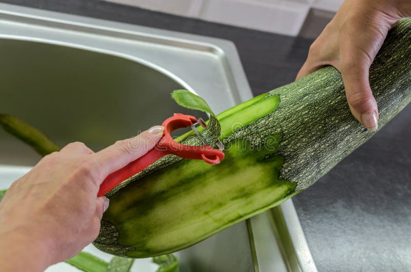 The Cook Peels a Large Zucchini with a Knife from the Peel Stock Photo