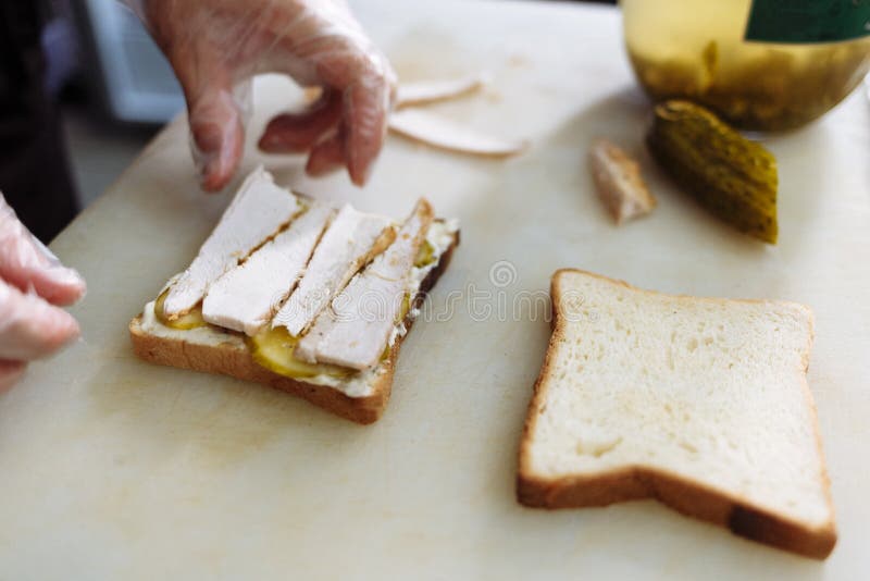 Cook in polyethylene gloves making a sandwich on a white board stock photos Cook in polyethylene gloves making a sandwich on a white board stock photos
