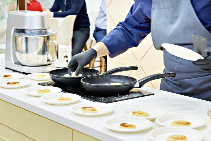 Cook prepares cheesecakes syrniki in frying pan royalty free stock image