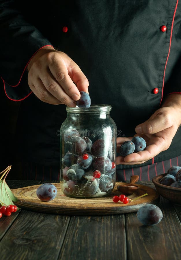 The cook prepares a sweet compote or fruit drink from ripe plums. Working environment on the kitchen table stock image