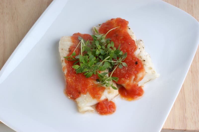 Cooked cod loins with tomato sauce stock image