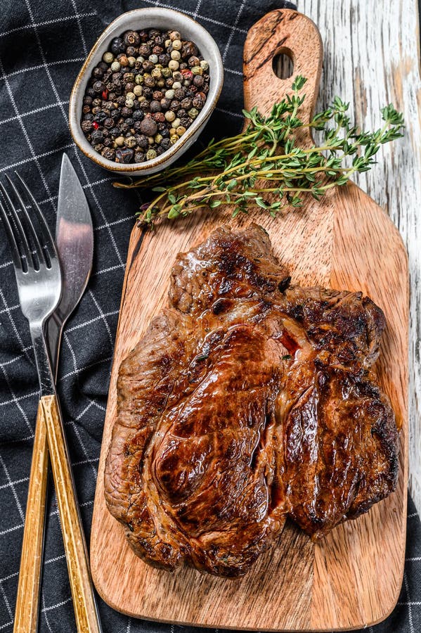 Cooked Grilled Chuck Eye Roll Steak on a Chopping Board. White