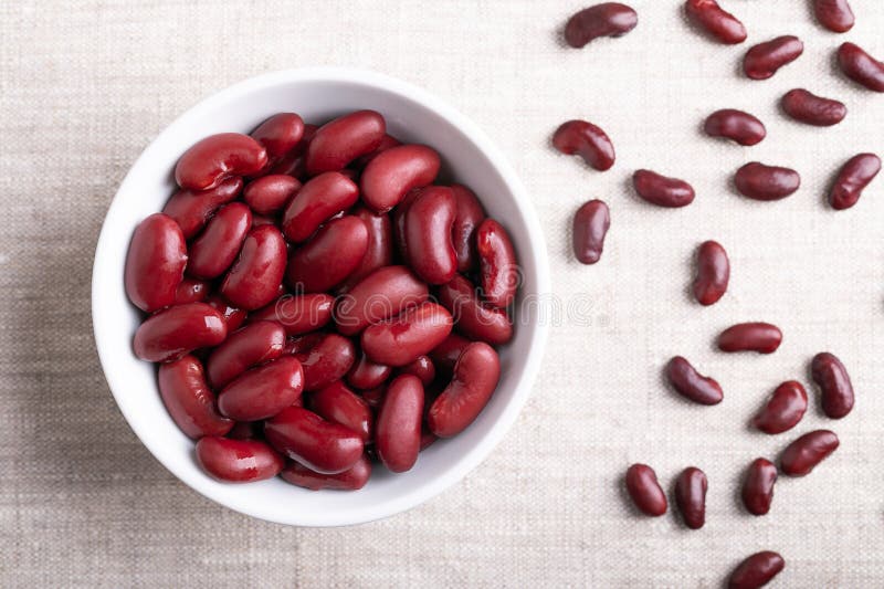 Kidney beans, cooked and canned beans in a white bowl on linen fabric stock image