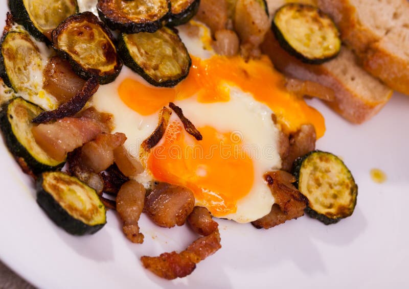 Cooked Scrambled Eggs with Zucchini and Fried Lard at Plate on Table