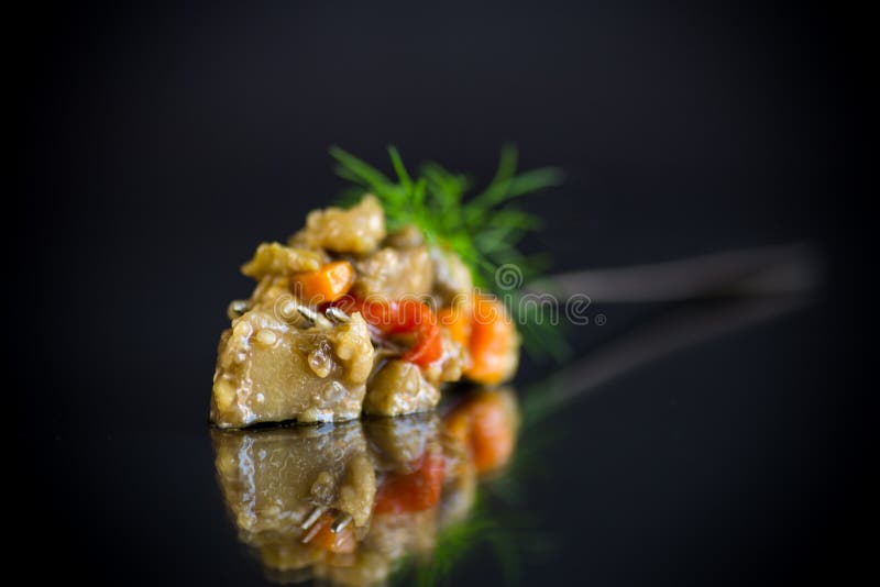 Cooked summer eggplant caviar with vegetables on black background