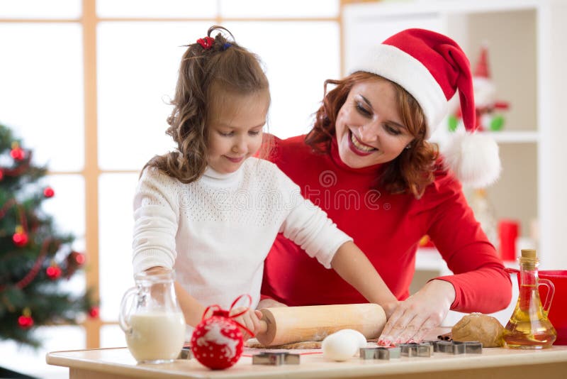 Cookies adoráveis do Natal do cozimento da menina e da mãe imagens de stock Cookies adoráveis do Natal do cozimento da menina e da mãe imagens de stock