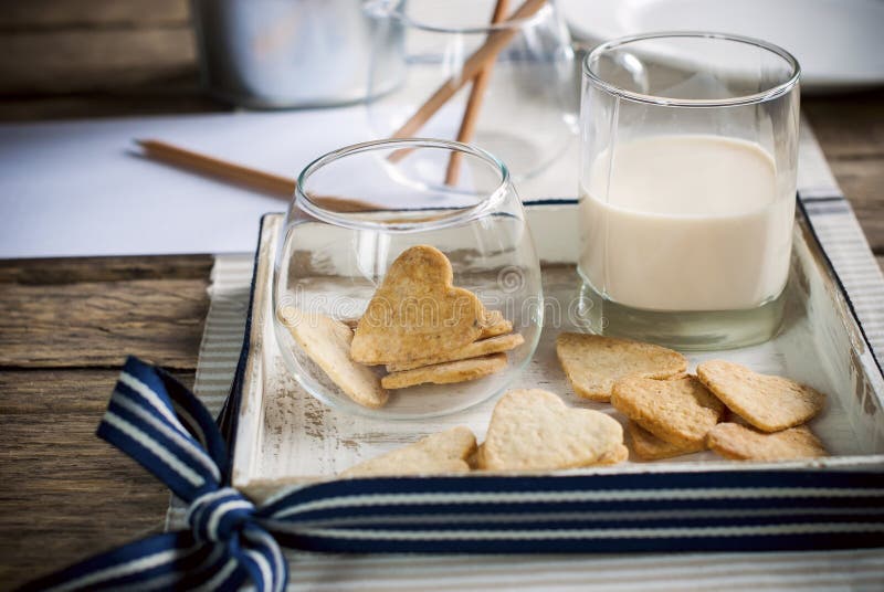 Cookies in the Shape of Hearts with milk on Wooden Table