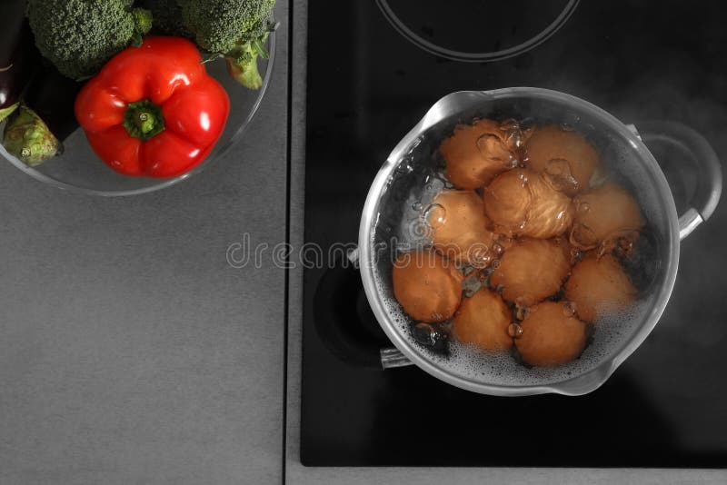 Cooking chicken eggs in pot on electric stove, top view.