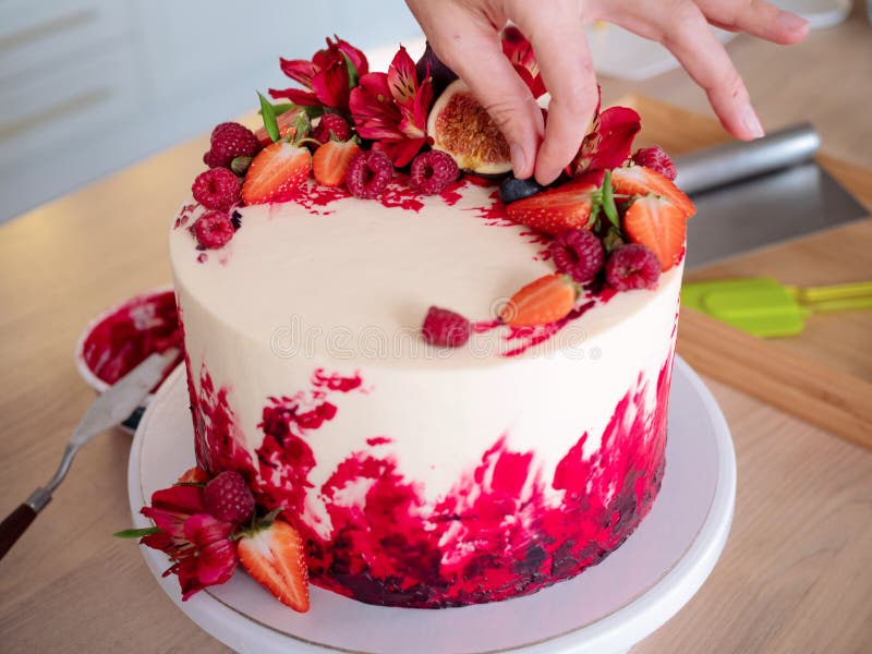 Cooking and decoration of cake with cream. Young woman pastry chef in the kitchen decorating red velvet cake