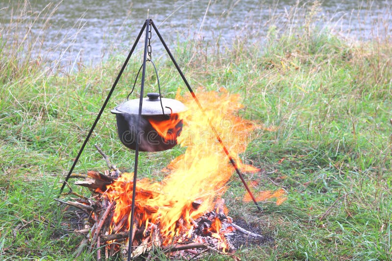 Cooking delicious tasty food outdoors on fire in pot in summer in good weather with wood from forest stock photos Cooking delicious tasty food outdoors on fire in pot in summer in good weather with wood from forest stock photos