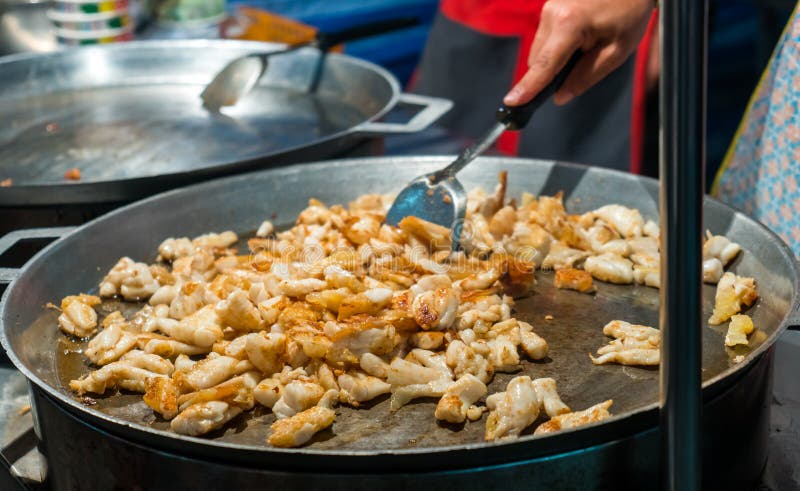 Cooking frying squid with egg in a big pan at market stall