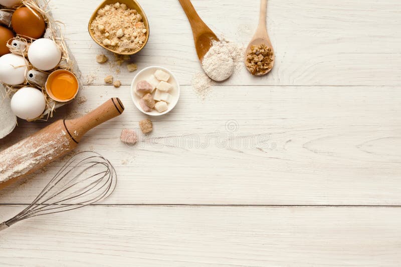 Cooking ingredients background. Border of flour, eggs, raisins, sugar and kitchen utensils on white rustic wood with copy space. Dough preparing and pastry concept, top view. Cooking ingredients background. Border of flour, eggs, raisins, sugar and kitchen utensils on white rustic wood with copy space. Dough preparing and pastry concept, top view