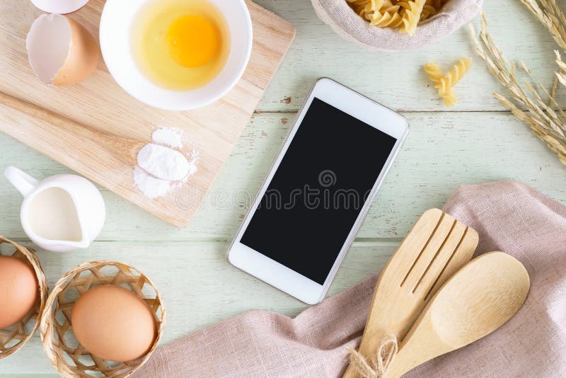Cooking ingredients, equipment and cellphone on green wooden background stock photo Cooking ingredients, equipment and cellphone on green wooden background stock photo