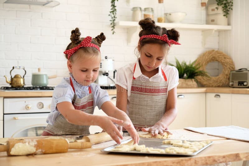 Cooking with kids. Happy funny children preparing the dough, bake cookies in the kitchen. Chef kids having fun in the kitchen. Warm sunny day.