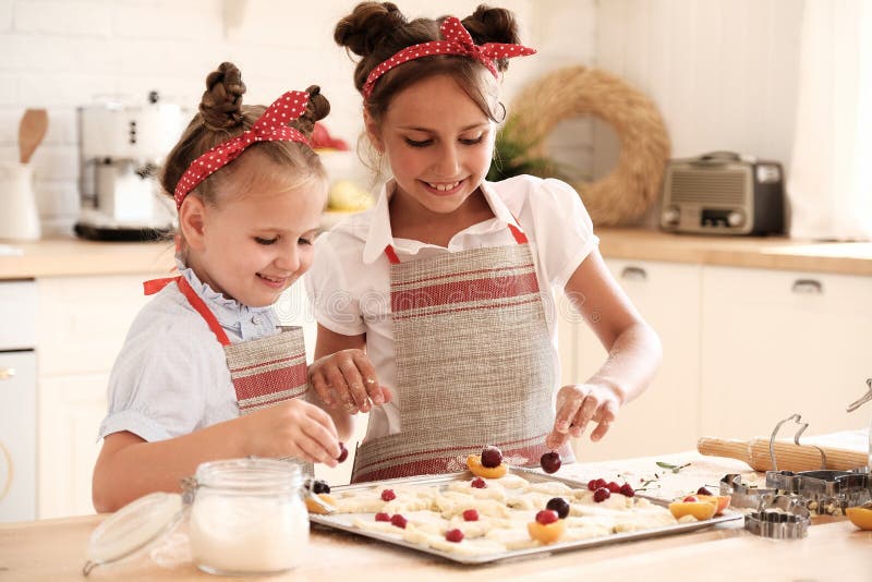 Cooking with kids. Happy funny children preparing the dough, bake cookies in the kitchen. Chef kids having fun in the kitchen. Warm sunny day.