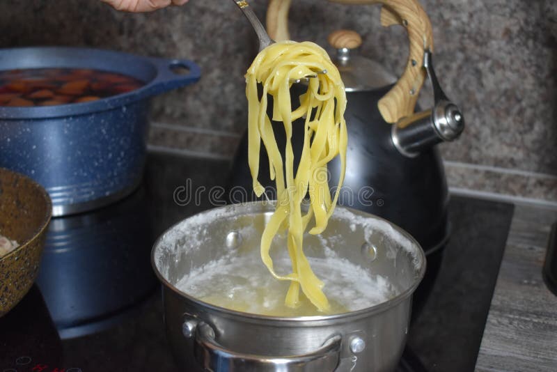 Cooking Long Pasta in a Saucepan on the Stove in Kitchen Stock Photo