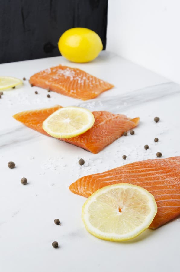 Cooking of raw tasty salmon with yellow lemon and pepper in the kitchen royalty free stock photo Cooking of raw tasty salmon with yellow lemon and pepper in the kitchen royalty free stock photo