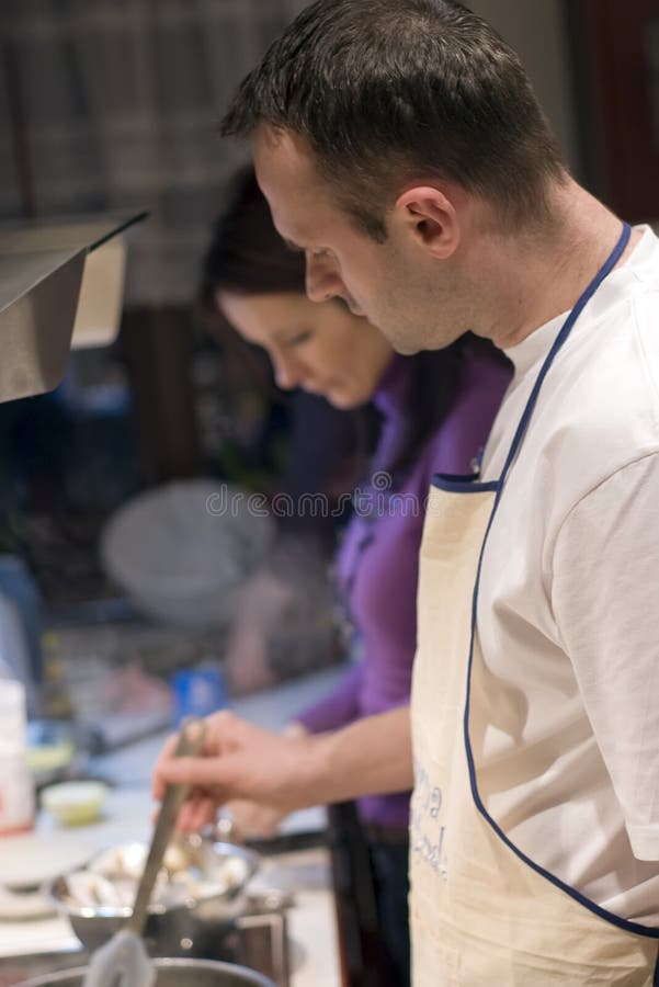 Muž a žena varenie spolu v kuchyni, obe zameraný na to, čo robia.
