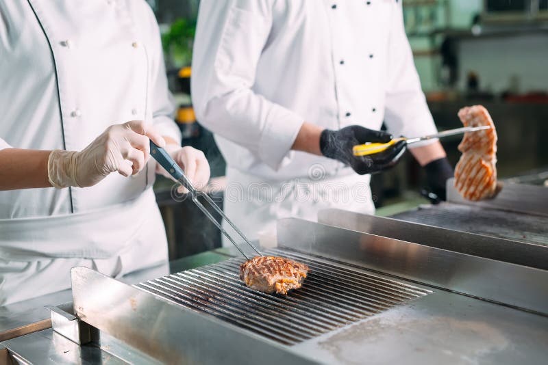 Cooks Roast Meat on the Stove in the Kitchen of a Restaurant or Hotel. Stock Image Image of