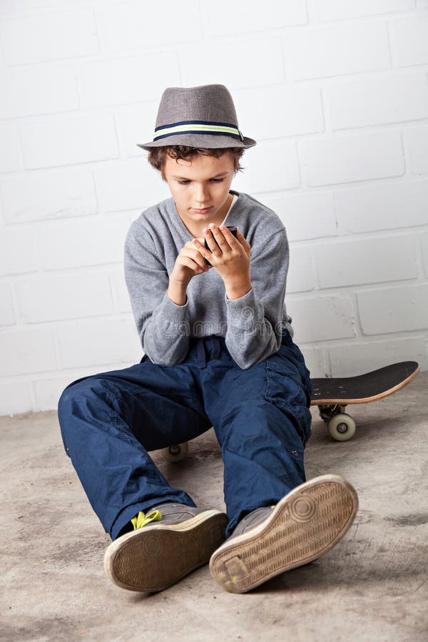 Cool Boy Sitting on His Skateboard, Holding a Smartphone Stock Photo ...
