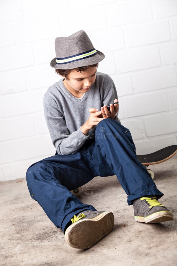 Cool Boy Sitting on His Skateboard, Holding a Smartphone Stock Photo ...