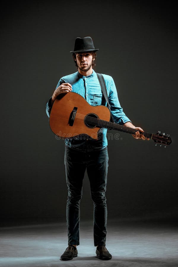 Cool guy standing with guitar on dark background