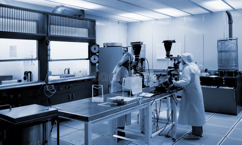 Due tecnici che lavorano in un laboratorio biotech guardando attraverso due microscopi in luce azzurro pallido.