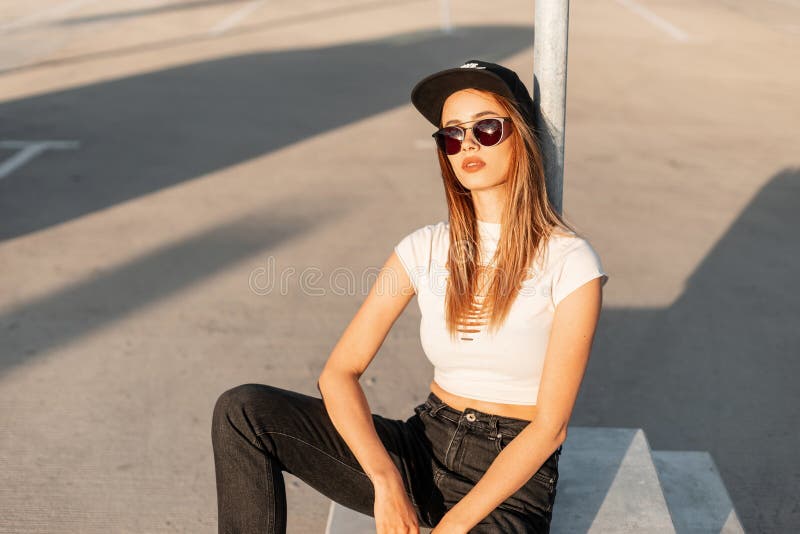 Cool pretty young woman hipster with sexy lips in fashion sunglasses in stylish black-white summer clothes from vogue collection