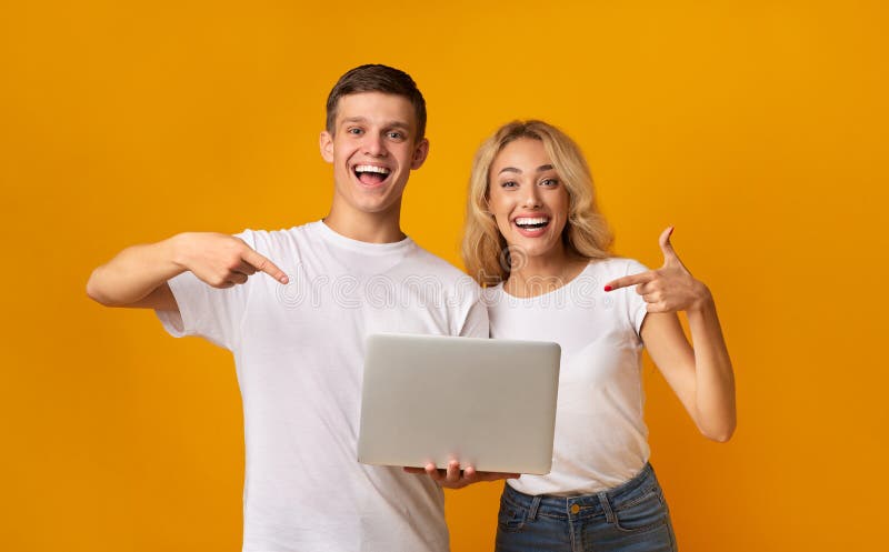 Happy youngsters holding laptop and pointing on it