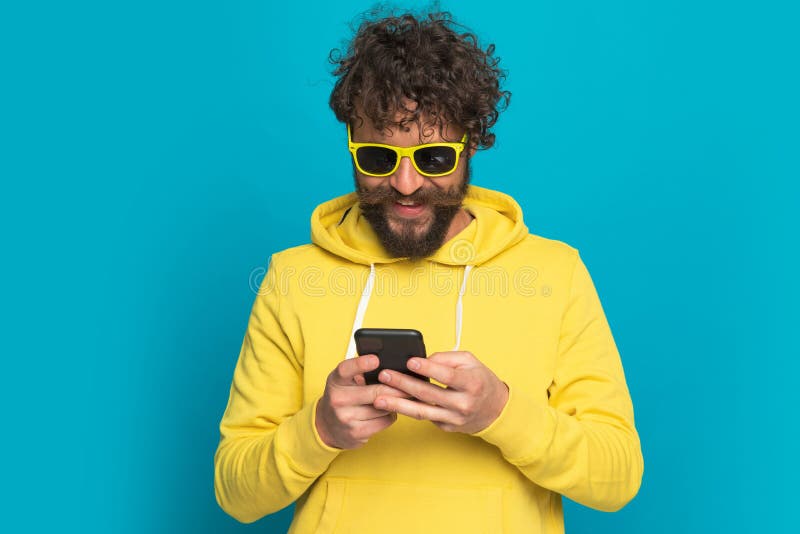 Cooler lässiger Mann mit langem Bart und Schnurrbart, das Telefon und SMS hält lizenzfreie stockfotos