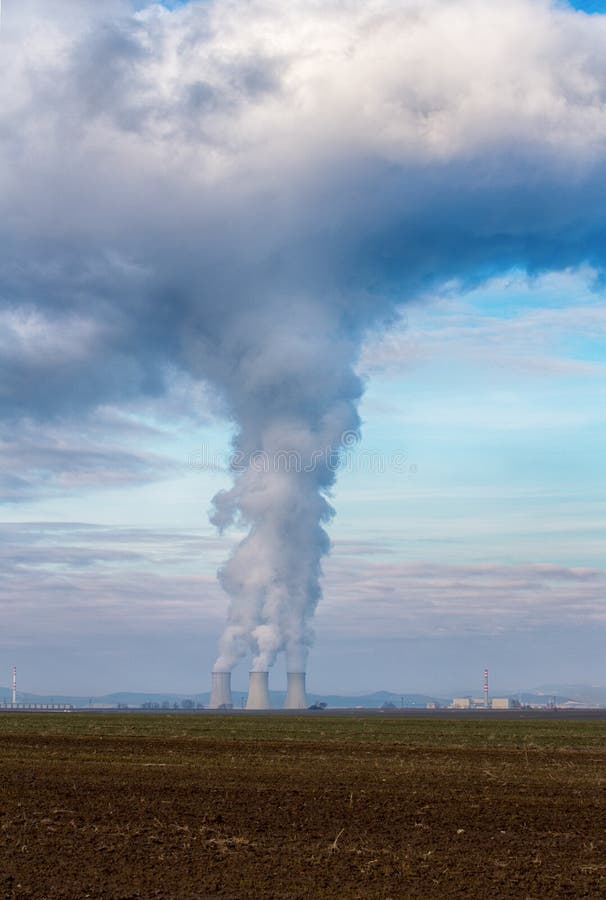 Chladiace veže jadrovej elektrárne Jaslovské Bohunice EBO na Slovensku. Mraky hustého dymu z komínov na modrej oblohe