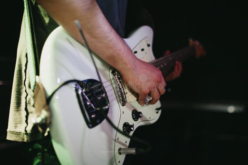 Coordonnée de l'homme jouant la guitare électrique blanche pendant un concert de rock indépendant photo libre de droits Coordonnée de l'homme jouant la guitare électrique blanche pendant un concert de rock indépendant photo libre de droits