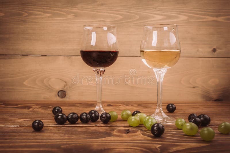 Copas de vino y uva rojas y blancas en la tabla de madera fotografía de archivo Copas de vino y uva rojas y blancas en la tabla de madera fotografía de archivo