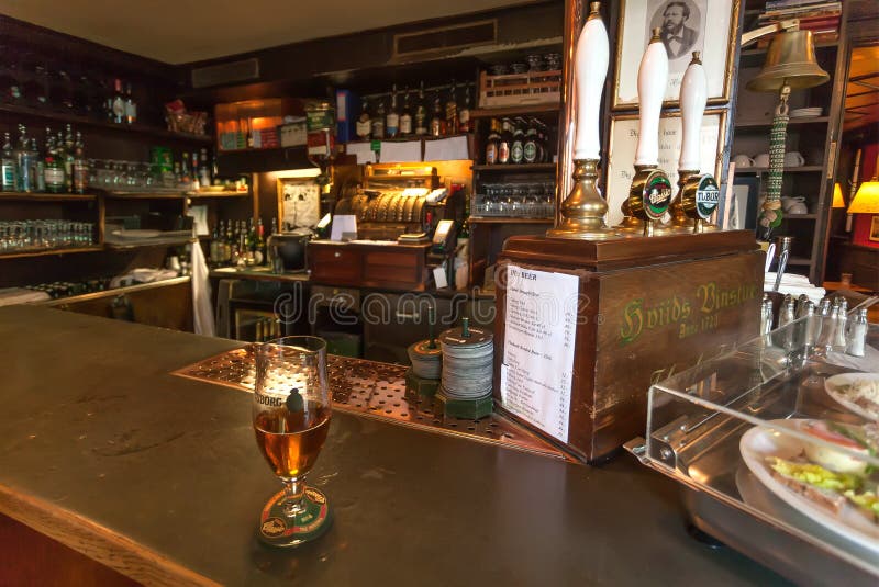 Bar counter with glass of beer, vintage interior, classic style utensils, snacks and bottlers