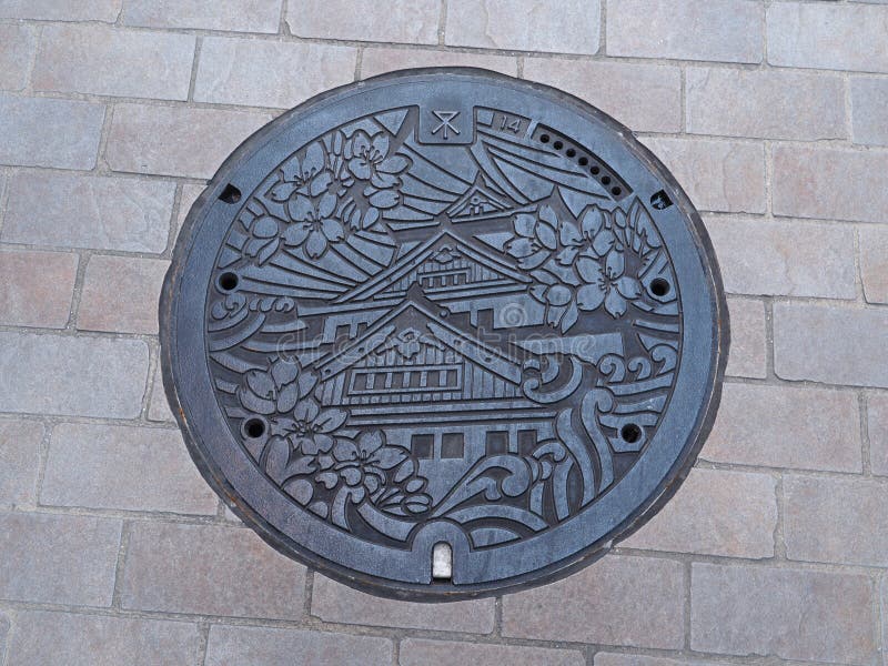 Copertura dello scolo della botola sulla via a Osaka, Giappone fotografia stock libera da diritti Copertura dello scolo della botola sulla via a Osaka, Giappone fotografia stock libera da diritti