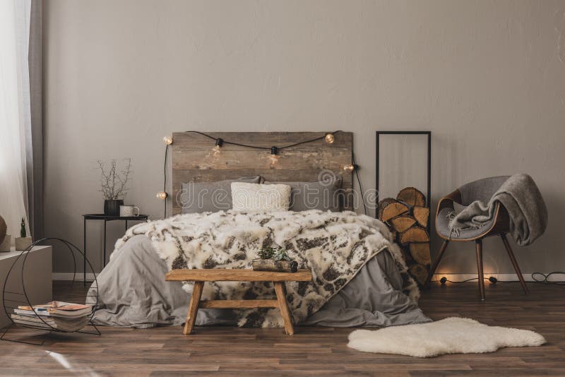 Copiare spazio sulla parete grigia vuota della camera da letto elegante all'interno con accenti di legno e letto di dimensioni re fotografia stock libera da diritti