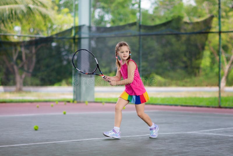 Copiii care joacă tenis pe teren în aer liber stock image