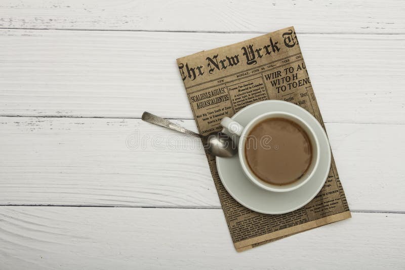 Copo branco com café preto e o jornal velho em um fundo arborizado branco Café em um fundo arborizado branco Vista de acima pl fotos de stock Copo branco com café preto e o jornal velho em um fundo arborizado branco Café em um fundo arborizado branco Vista de acima pl fotos de stock