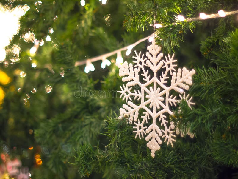 Copo de nieve blanco en la decoración del color verde del árbol de navidad por la iluminación del Año Nuevo con el fondo del boke foto de archivo Copo de nieve blanco en la decoración del color verde del árbol de navidad por la iluminación del Año Nuevo con el fondo del boke foto de archivo