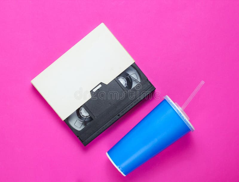 Copo de papel com palha, gaveta video no fundo cor-de-rosa Cultura Pop 80s, estilo retro Vista superior fotografia de stock royalty free Copo de papel com palha, gaveta video no fundo cor-de-rosa Cultura Pop 80s, estilo retro Vista superior fotografia de stock royalty free