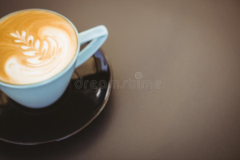 Copo do cappuccino com arte do café na tabela de madeira foto de stock Copo do cappuccino com arte do café na tabela de madeira foto de stock