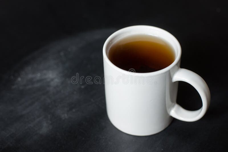 Copo do chá quente em uma placa preta fotos de stock Copo do chá quente em uma placa preta fotos de stock