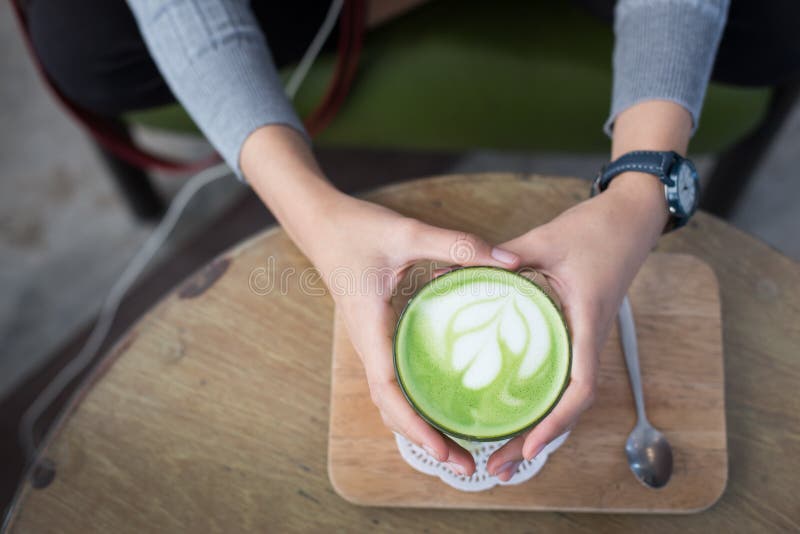 Uma chávena de Matcha com chá verde na mão de uma mulher foto de stock