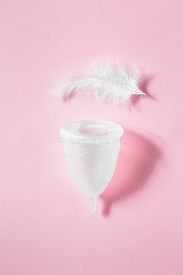 Copo menstrual rosa de silicone com rosa sobre fundo branco, conceito de  menstruação
