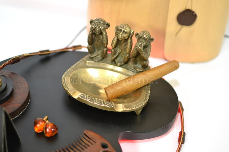 Copper Ashtray with Cigar and Monkeys and Amber Earrings Stock Photo